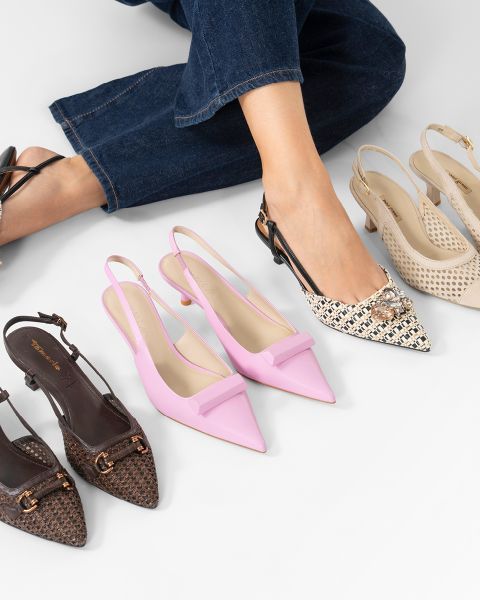 Eine Person, die Jeans trägt, probiert spitze Slingback-Absätze an, umgeben von drei weiteren Paaren modischer Slingback-Schuhe in verschiedenen Farben und Texturen.