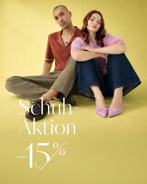 Ein Mann und eine Frau sitzen auf einem gelben Boden; er trägt Freizeitkleidung und schwarze Schuhe, sie trägt ein rosa Oberteil, Jeans und rosa Absätze. Text: Schuh-Aktion -15%.