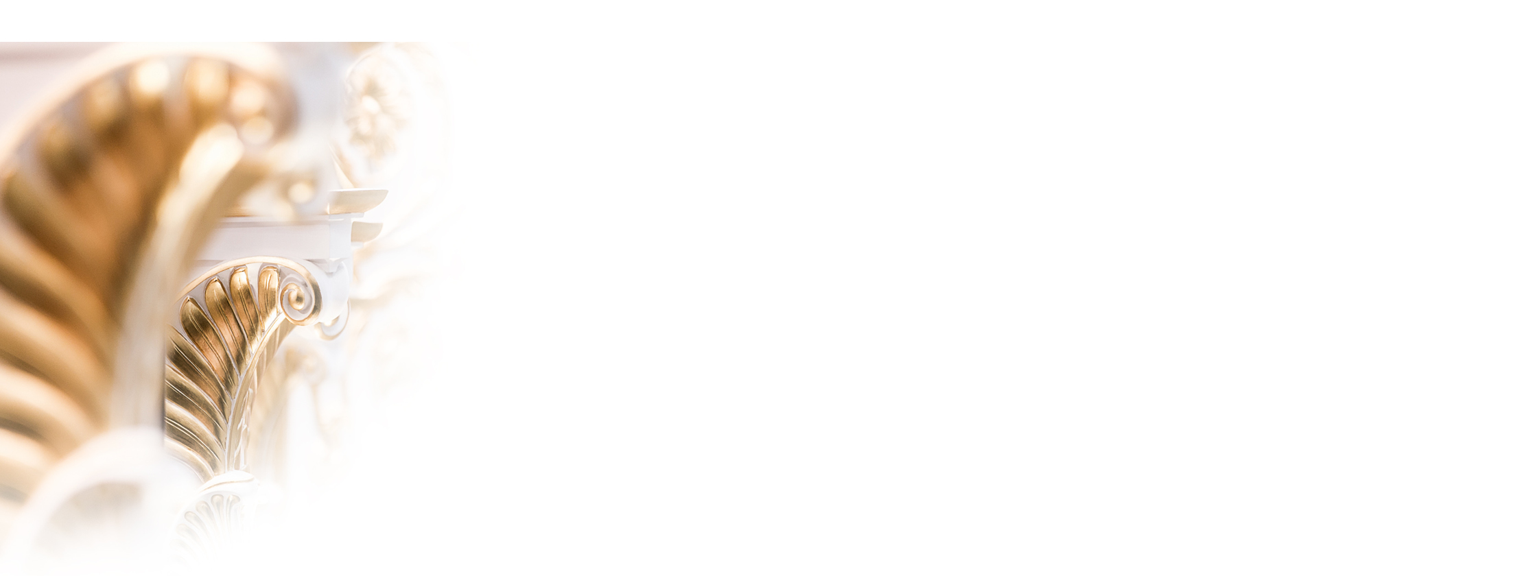 Nahaufnahme von verschnörkelten, gold- und weißverzierten architektonischen Details, die rechts in einen weißen Hintergrund übergehen.