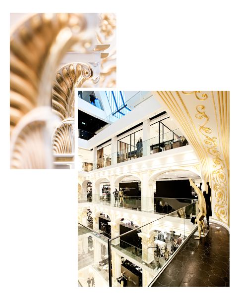 Verschnörkelte goldene und weiße Details in einem modernen, mehrstöckigen Einkaufszentrum mit Glasgeländern und stilvollem Dekor.