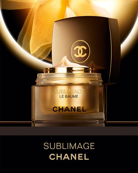 Ein Cremetiegel von Chanel Sublimage Le Baume mit offenem Deckel vor einem leuchtenden goldenen Hintergrund.