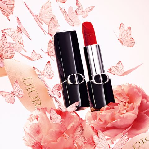 Ein roter Dior-Lippenstift mit schwarzer Hülle ist umgeben von rosa Blumen, Schmetterlingen und einem Band mit dem Dior-Logo.
