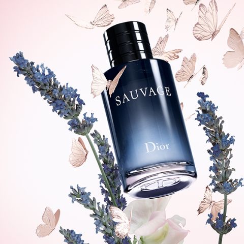 Ein Flakon des Parfums Dior Sauvage, umgeben von Lavendelzweigen und zarten Schmetterlingen auf einem hellrosa Hintergrund.
