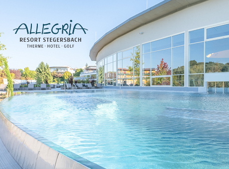 Außenpool mit klarem, blauem Wasser neben einem modernen Glasgebäude im Allegria Resort Stegersbach, umgeben von Grün unter einem klaren Himmel.