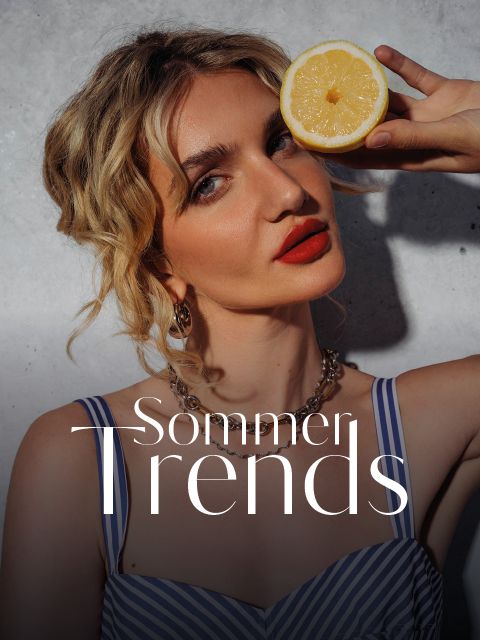 Eine Frau in einem gestreiften Kleid hält eine halbe Zitrone neben ihr Gesicht und trägt knallroten Lippenstift. Die Bildunterschrift lautet „Sommer-Trends“. Sonnenlicht wirft Schatten an die Wand.