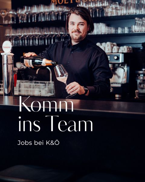 Ein Barkeeper schenkt Wein in ein Glas an einer Bar ein. Der Text lautet: "Komm ins Team. Jobs bei K&Ö.