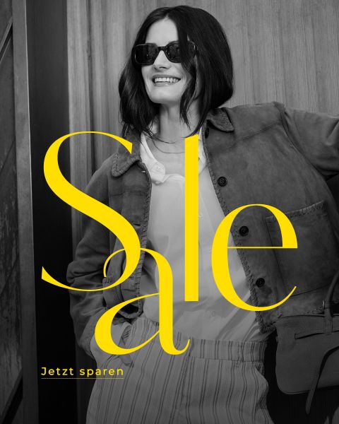 Eine lächelnde Frau mit Sonnenbrille und elegantem Outfit steht an einer Wand. In großer gelber Schrift steht "Sale". Kleinerer Text: "Jetzt sparen.".