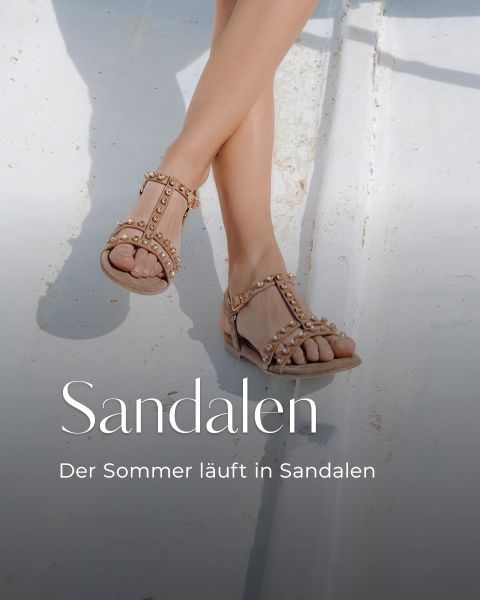 Eine Person, die nudefarbene Sandalen mit Nieten trägt, sitzt mit gekreuzten Beinen; der Text lautet: „Sandalen. Der Sommer läuft in Sandalen.“.