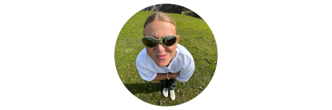 Eine Person mit Sonnenbrille und weißem Hemd steht auf dem Rasen und blickt mit einem verspielten Gesichtsausdruck in die Kamera. Das Foto wurde mit einem Fischaugenobjektiv aufgenommen.