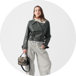 Eine Frau in einer schwarzen Lederjacke und einer karierten Hose, die eine Handtasche mit Leopardenmuster in der Hand hält, steht vor einem hellgrauen Hintergrund.