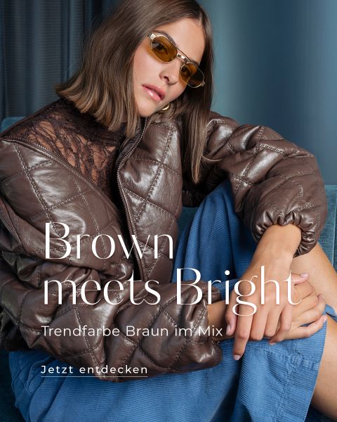 Eine Frau in einer braunen Steppjacke und mit getönten Brillen sitzt auf einem Sofa; der Text lautet: „Braun trifft auf Hell. Trendfarbe Braun im Mix. Jetzt entdecken.“.