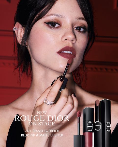 Eine Frau trägt den Lippenstift „Rouge Dior“ auf und hält den Applikator nahe an ihre Lippen. Drei Lippenstifthülsen sind abgebildet. Der Text wirbt für einen 24-Stunden-Lippenstift, der nicht abfärbt, die Lippen sanft verwischt und ein mattes Finish bietet.