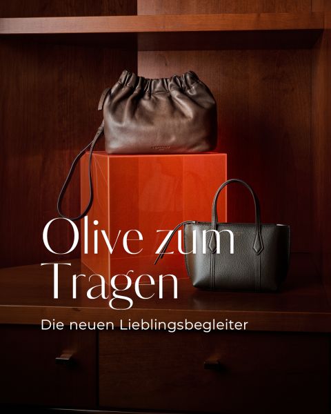 Zwei Handtaschen, eine braune und eine olivfarbene, stehen auf einem Holzregal, daneben steht der deutsche Text: „Olive zum Tragen. Die neuen Lieblingsbegleiter.“.