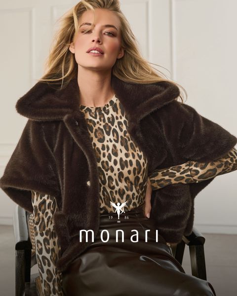 Eine Frau in einem Cape aus Kunstfell über einem Oberteil mit Leopardenmuster und einem braunen Rock sitzt und posiert; unten sind „monari“ und das Logo zu sehen.