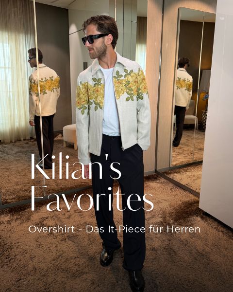 Ein Mann mit Sonnenbrille und einem geblümten Overshirt steht in einem stilvollen Raum mit Spiegeln. Der Text lautet: „Kilians Favoriten: Overshirt – Das It-Piece für Herren.“.