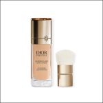Eine Dior Prestige-Foundation-Flasche mit goldenem Verschluss und einem dazu passenden goldenen Make-up-Pinsel mit weißen Borsten, beide vor einem weißen Hintergrund.