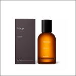 Neben der dunkelgrauen Schachtel steht eine braune Glasflasche mit dem Parfüm „Aesop Gleam“; beide sind mit minimalistischen weißen Schriftzügen auf weißem Hintergrund versehen.