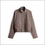 Hellbraune Jacke mit Reißverschluss, langen Ärmeln, zwei Vordertaschen und einem elastischen Saum, abgebildet auf weißem Hintergrund.