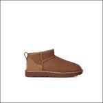 Ein brauner Wildleder-Stiefelette mit flacher Sohle, sichtbaren Nähten und einer Zuglasche an der Ferse, dargestellt vor einem weißen Hintergrund.