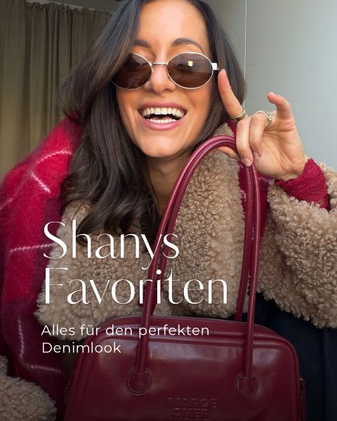 Eine lächelnde Frau mit Sonnenbrille und rotem Mantel hält eine rote Handtasche in der Hand. Der Text lautet: „Shanys Favoriten. Alles für den perfekten Denim-Look.“.