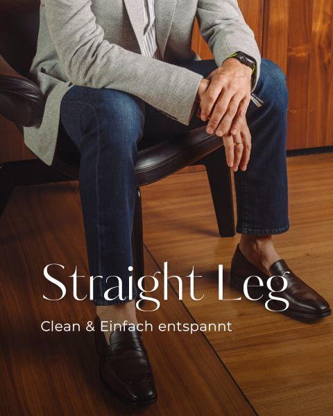 Person seated in a chair wearing a light gray blazer, dark jeans, and brown loafers; large text reads 'Straight Leg' (fashion ad).